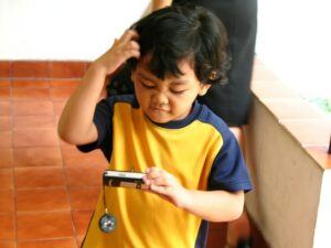 boy looking at phone scratching head